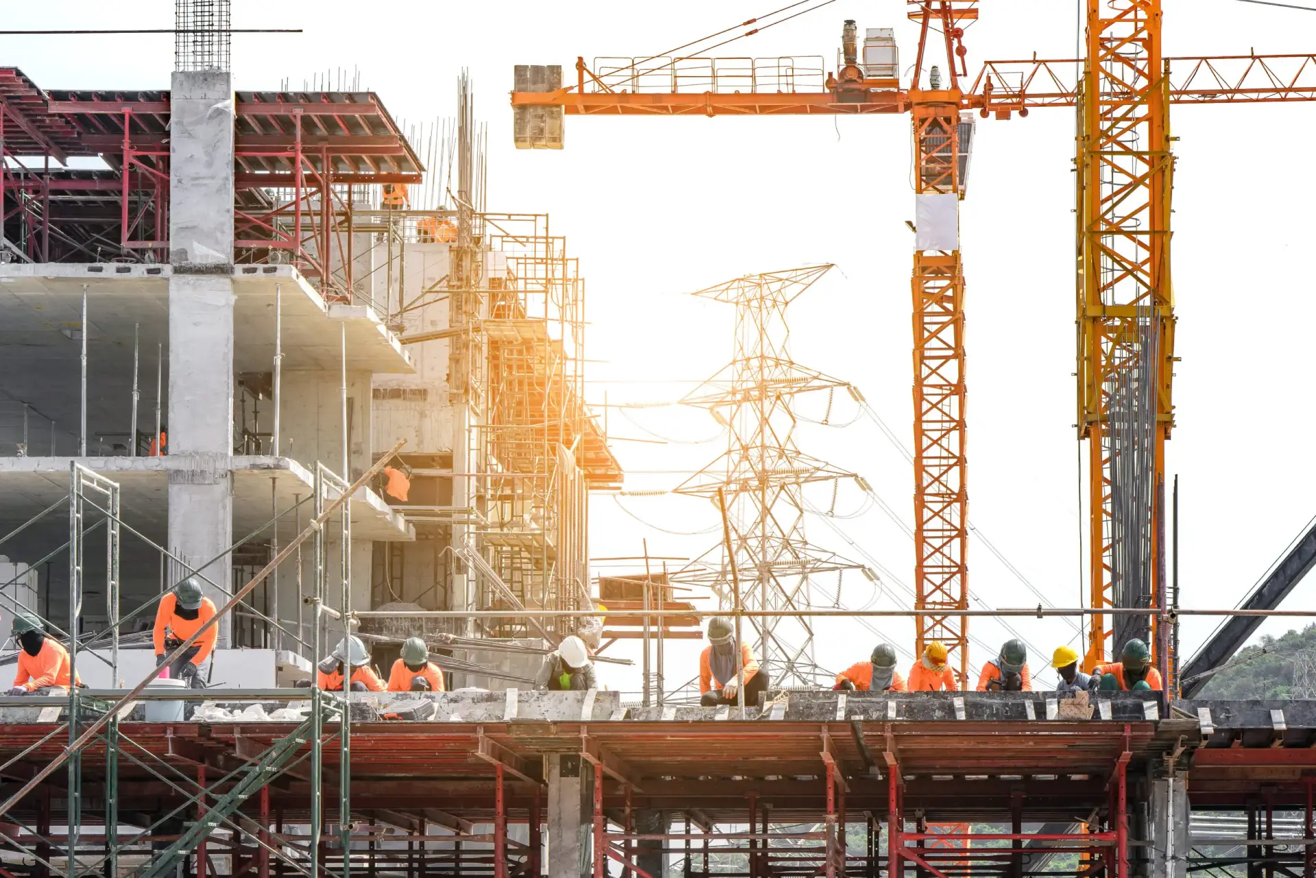 Construction workers on building site with cranes.